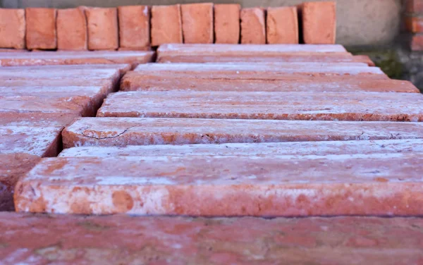 wooden pallet plenty of old stacked red bricks. The bricks are ordered in many rows.