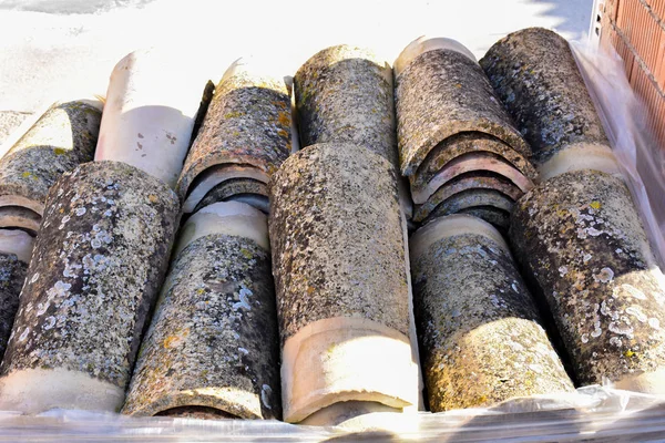 Σωρούς των παλαιών κεραμίδια σε πολλές σειρές με διαφορετικό αριθμό σε κάθε στήλη. Η αρχαία πλακίδια βάφονται με σκόνη και λειχήνες να μεταρρυθμίσει ένα παλιό σπίτι. — Φωτογραφία Αρχείου