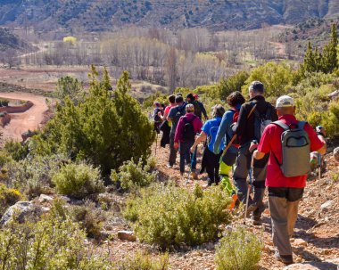 Grup kum ve taşların bir dağ inanılmaz bir manzara ile arka planda yürüyen muhteşem güneşli bir günde yola trekking renkli sırt çantası ile yetişkin insan.