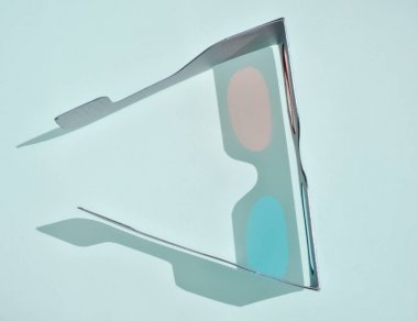 sinemada film görerek ucuz ağaç optik algı oluşturmak için karton ve plastik ile yapılan eğlenceli bir 3d gözlük yakın. Gözlük mavi arka plan üzerinde kırmızı ve mavi renklerde iki lens var.