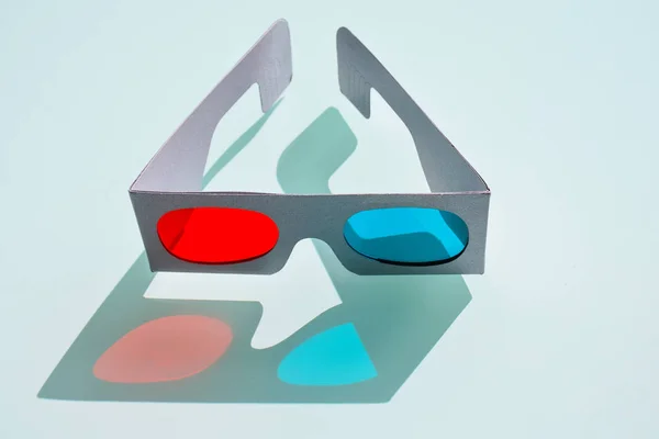 close up of a fun 3d glasses made with cardboard and plastic to create cheap tree optical perception by eyes seeing films at cinema.The glasses have two lens in red and blue colors on blue background.