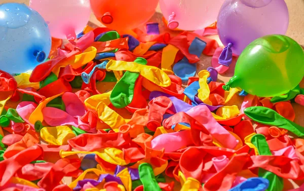 many colorful balloons on the tiles of a terrace. Some balloons are deflated and other balloons are full of water and air to prepare a fight in sunny day of summer. Horizontal picture