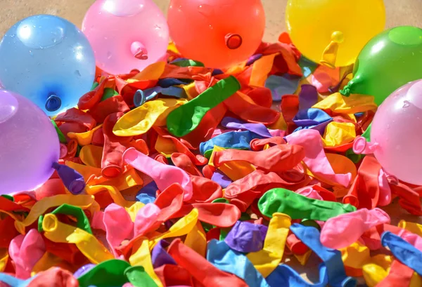 Molti palloncini colorati sulle piastrelle di una terrazza. Alcuni palloncini sono sgonfiati e altri palloncini sono pieni di acqua e aria per preparare una lotta nella giornata di sole dell'estate. Quadro orizzontale — Foto Stock