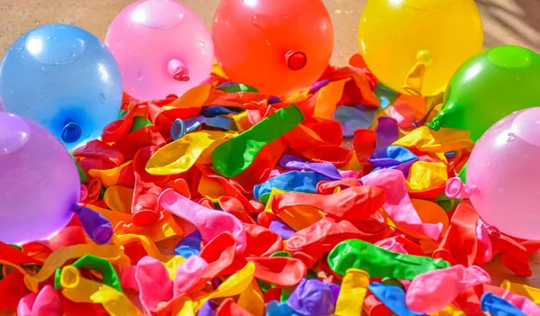 many colorful balloons on the tiles of a terrace. Some balloons are deflated and other balloons are full of water and air to prepare a fight in sunny day of summer. Horizontal picture