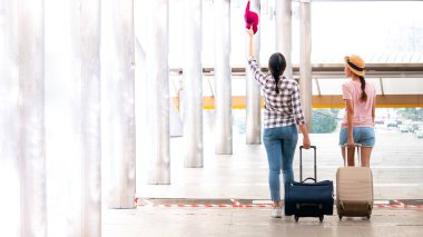 Yürüyüş ve Bagaj çanta çanta mutlu tatil tatil ile sürükleyerek iki genç turist kız.