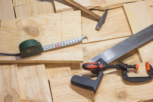 Hammer, saw and clamp lie on a wooden background. Construction Tools — Stock Photo, Image