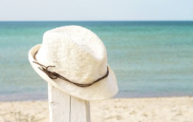 Boho stil beyaz hasır şapka deniz arka plan üzerinde beyaz bir stand. tropikal dinlenme ve seyahat kavramı. metin için boş alan