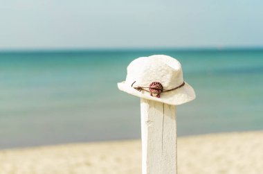 Boho-stil beyaz hasır şapka kırmızı bir kabuk ile beyaz bir stand. tatil tropikal kavramı. metin için boş alan