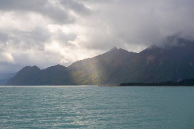 Eylül 2019 'da Seward, Alaska AK, ABD' deki Kenai Fjords Ulusal Parkı 'nda Aialik Buzulu yakınlarındaki Glacier Dağı üzerindeki güneş ışığı.