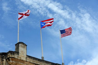 Castillo de San Cristobal, San Juan, Porto Riko 'da bayraklar dalgalanıyor. Soldan sağa üç bayrak Burgundy Cross, Porto Riko bayrağı ve ABD bayrağı. 