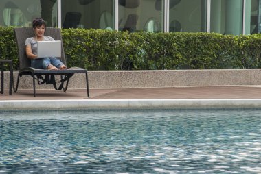 Bir laptop havuzun yanında oturan kadın