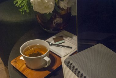 Beyaz çay bardağı gül vazo ile ahşap bir masa üzerine yerleştirilen aç 