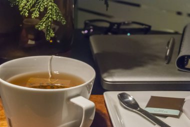 Beyaz çay bardağı gül vazo koydum ahşap bir masa üzerinde lapto vardır