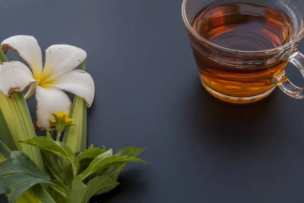 1 tazza di tè e una varietà di fiori disposti su un tavolo nero — Foto Stock