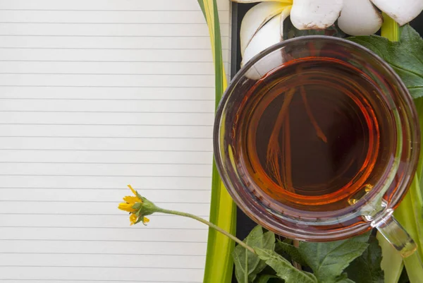 Notebook és tea bögre virágokkal elhelyezett együtt — Stock Fotó