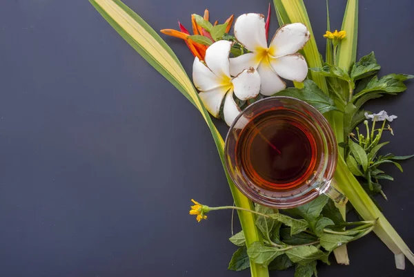 1 bicchiere di tè posto in vari fiori sul tavolo nero — Foto Stock