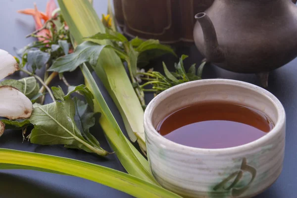 お茶セットと黒いテーブルの上の花 — ストック写真