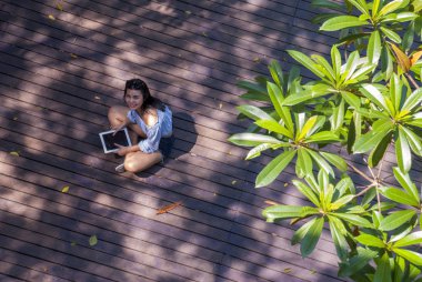 Kız bahçede otururken tablet üzerinde oturdu.