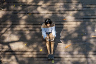 Kız bahçede otururken tablet üzerinde oturdu.