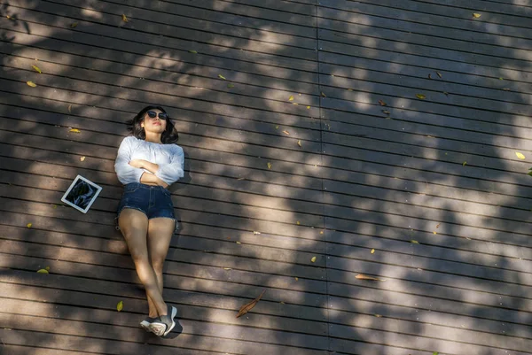 La chica se sentó en la tableta mientras estaba sentada en el jardín . — Foto de Stock