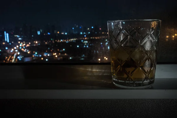 Whisky sklenice je umístěn vedle okna v hotelovém pokoji. — Stock fotografie