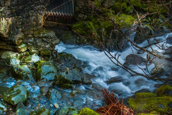 Un pequeño puente de piedra junto al río por la noche — Foto de Stock