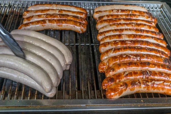 Salsichas alemãs a guinchar sobre as brasas na churrasqueira . — Fotografia de Stock