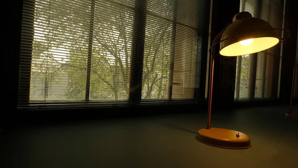 Yellow desk lamp on a beautiful green table Near the window.