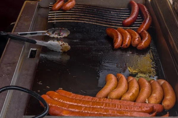 Fried sausages in big frying pan at a seasonal fair. — Stock Photo, Image