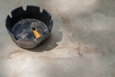 Siyah seramik kül tablası ve sigara izmaritleri söndürülür.