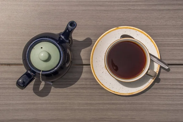 Filiżanka herbaty z czajniczek na drewnianym stole. — Zdjęcie stockowe