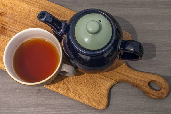 Xícara de chá com bule em uma mesa de madeira . — Fotografia de Stock