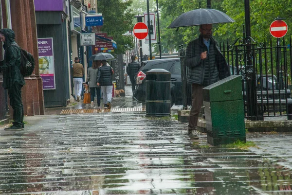 Pedestres protegem-se da chuva com guarda-chuvas durante — Fotografia de Stock