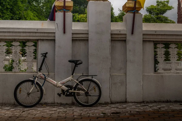 Белый велосипед, припаркованный на тротуаре у стены храма . — стоковое фото