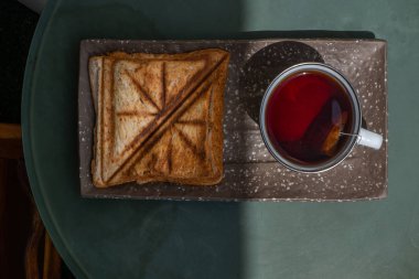 Kahvaltı-sandviç ve fincan çay seramik tepsi üzerinde. 