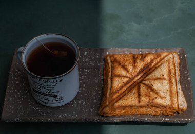 Kahvaltı-sandviç ve fincan çay seramik tepsi üzerinde. 