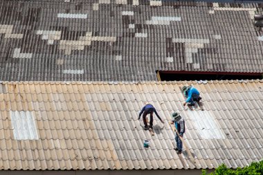Bangkok, Tayland - 13 Haziran 2020: Hasarlı fabrikanın çatısındaki fayansları tamir eden üç işçi.