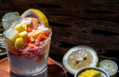 Süt ve yulaf ezmeli tropik taze meyve salatası ve koyu arkaplanda mısır. Sağlıklı bir kahvaltı, sağlıklı bir vejetaryen yemeği. Seçici odak.