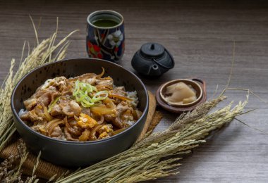 Japon domuz pirinci kasesi yumurta ve soğanlı (Donburi) turşulu zencefil ve ahşap masada yeşil çay ile servis edilir. Japon yemek tarzı..