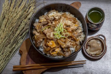 Japon domuz pirinci kasesi yumurta ve soğanlı (Donburi) turşulu zencefil ve ahşap masada yeşil çay ile servis edilir. Japon yemek tarzı..