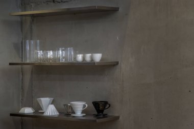 Fincan kahvesi ahşap raflar ve fincanlar asılıydı. Arka plan, fotokopi alanı olan çıplak beton duvarlardı. Minimalist tarz dekorasyon tasarımı. Tam olarak odaklanamıyorum..