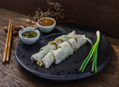 Tatlı soslu Tayland böreği ve siyah tabakta taze soğan. Seçici odak.