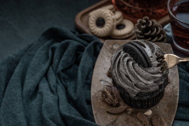 Koyu mavi kumaşlı bir fincan meyveli çayla Orio keki. Yukarıdan belirsiz görünüm.