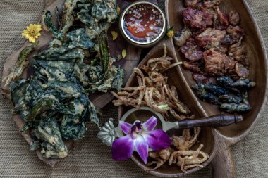 Tahta tepside tatlı sosla servis edilen gevrek çiçekler, çıtır otlar ve çıtır sebzeler..