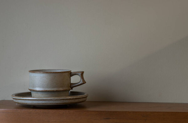 Ceramic mug handmade on the wooden shelf on wall of living room. Home decor. Space for text. Selective focus.