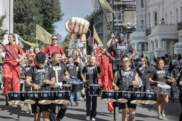 London, UK - Aug 25, 2025 -  "Jesus '25" music group wearing a black T-shirt playing a set of drums to participate and celebrate their faith through music and performance in the Notting Hill Carnival. use it as your Wallpaper, Poster and Space.