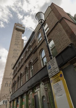 Batı Londra, İngiltere - 23 Ağustos 2025 - Kemerli pencereli eski bir tuğla bina manzarası, park işaretli bir sokak lambası ve arka planda Trellick Kulesi 'nin belirgin bir bölümü. Duvar kağıdı, poster ve kopyalama alanı olarak kullan, Sele