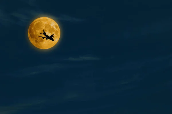 Flying airplane on full moon background