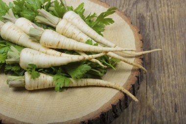 ahşap yüzeyüzerinde yaprakları ile maydanoz kökleri