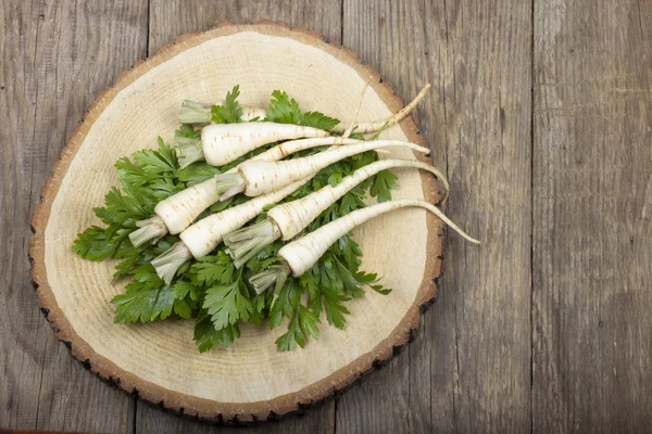 ahşap yüzeyüzerinde yaprakları ile maydanoz kökleri